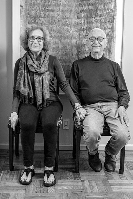 Elderly couple holding hands sitting together