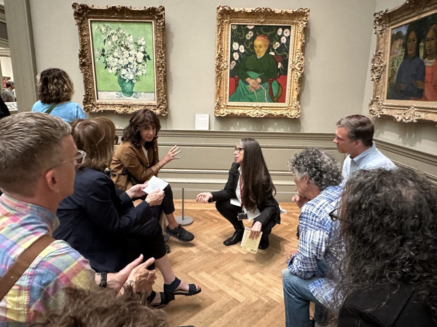 A group listens to a guide in an art gallery near paintings.