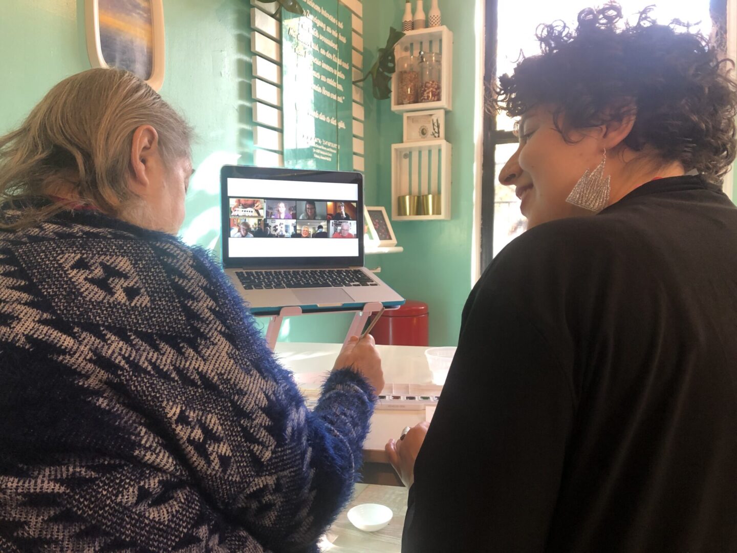 Two women engaging with a video call on a laptop indoors.