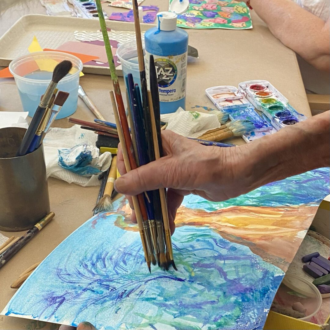Person painting with brushes and watercolors.