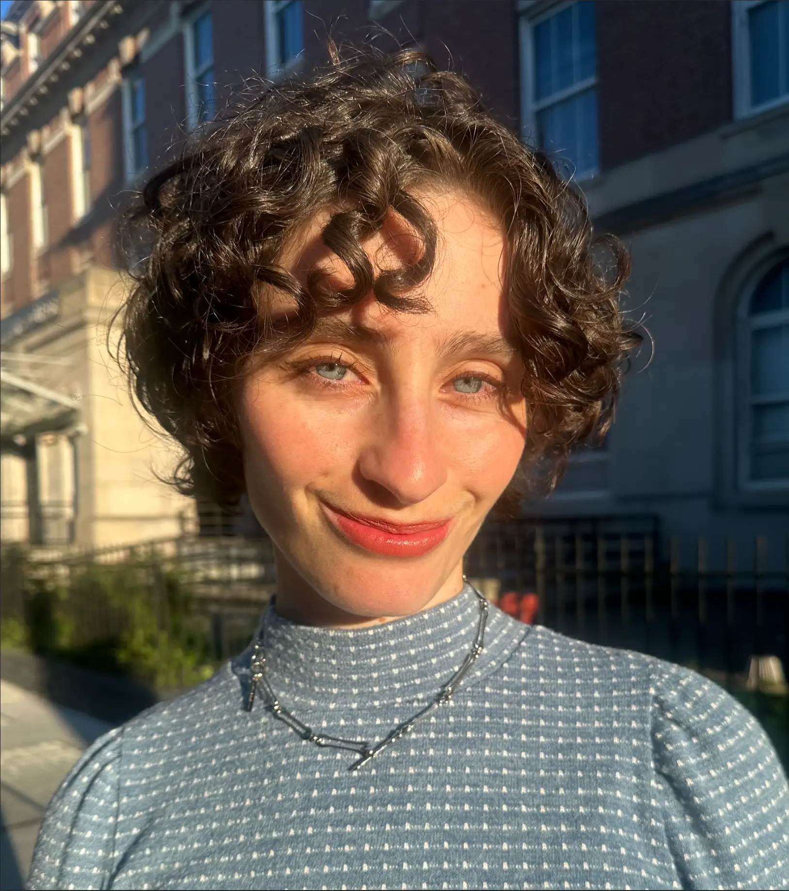 Young woman smiling in the sunlight outdoors.