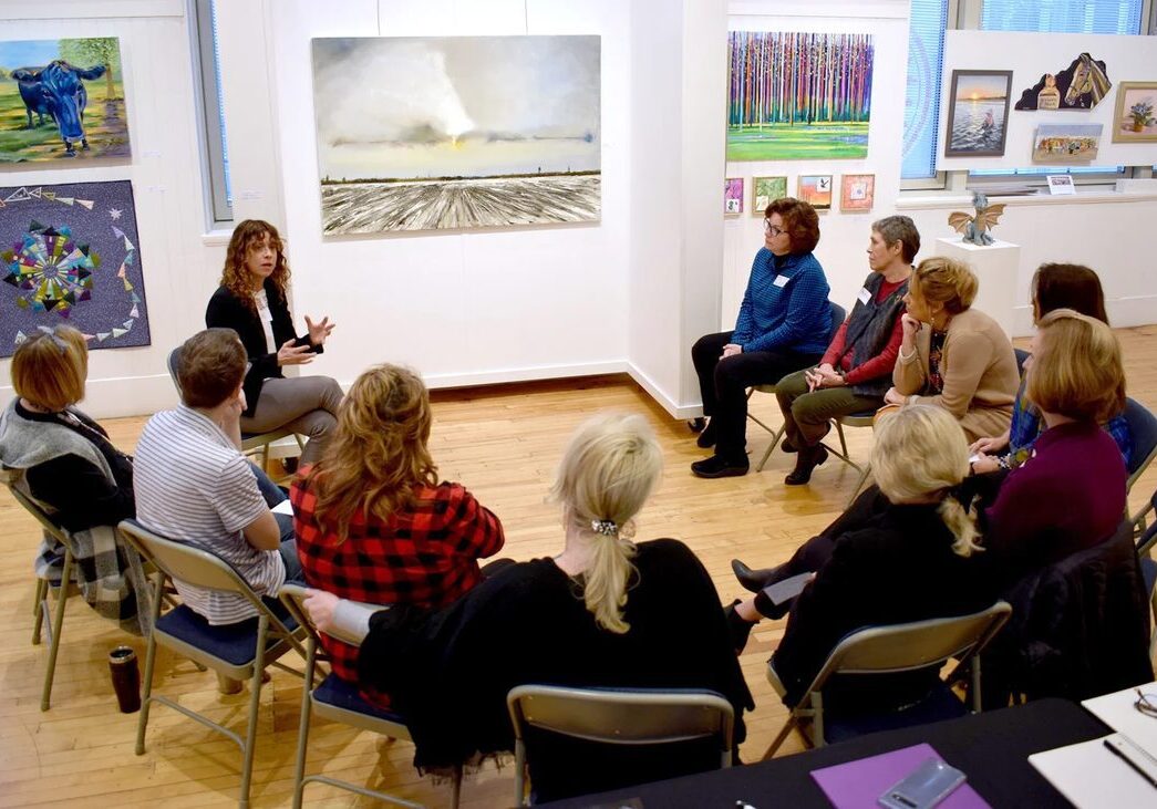 People seated discussing paintings
