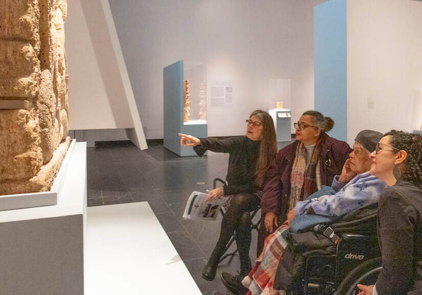 Museum visitors observing ancient sculpture